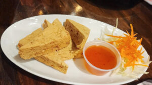 Plate of crispy fried tofu at The Baht served golden brown with dipping sauce