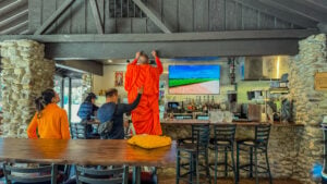 Buddhist monk performing a traditional blessing ceremony inside The Baht Thai Restaurant in Gatlinburg, Tennessee, with staff assisting.