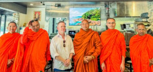 Group portrait of Buddhist monks and a guest inside The Baht Thai Restaurant in Gatlinburg, Tennessee.